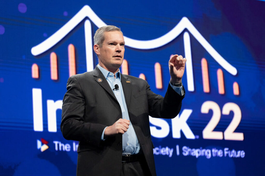 A person delivering a presentation at a conference with the event name "innovention week '22 - the innovation society | shaping the future" displayed in the background.