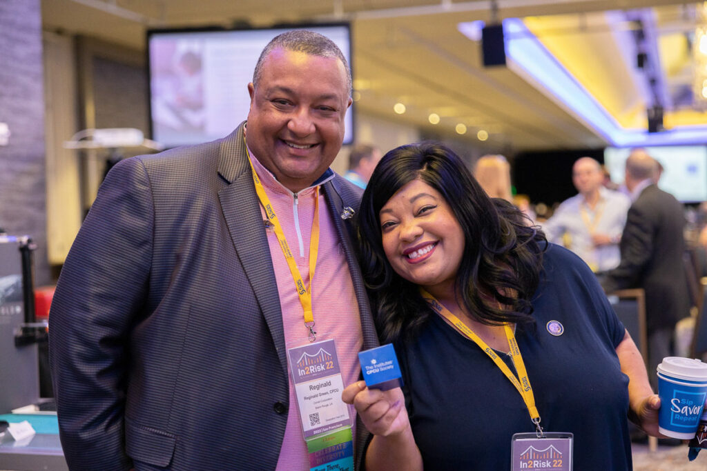 Two cheerful event attendees proudly displaying a card and enjoying a social moment together.