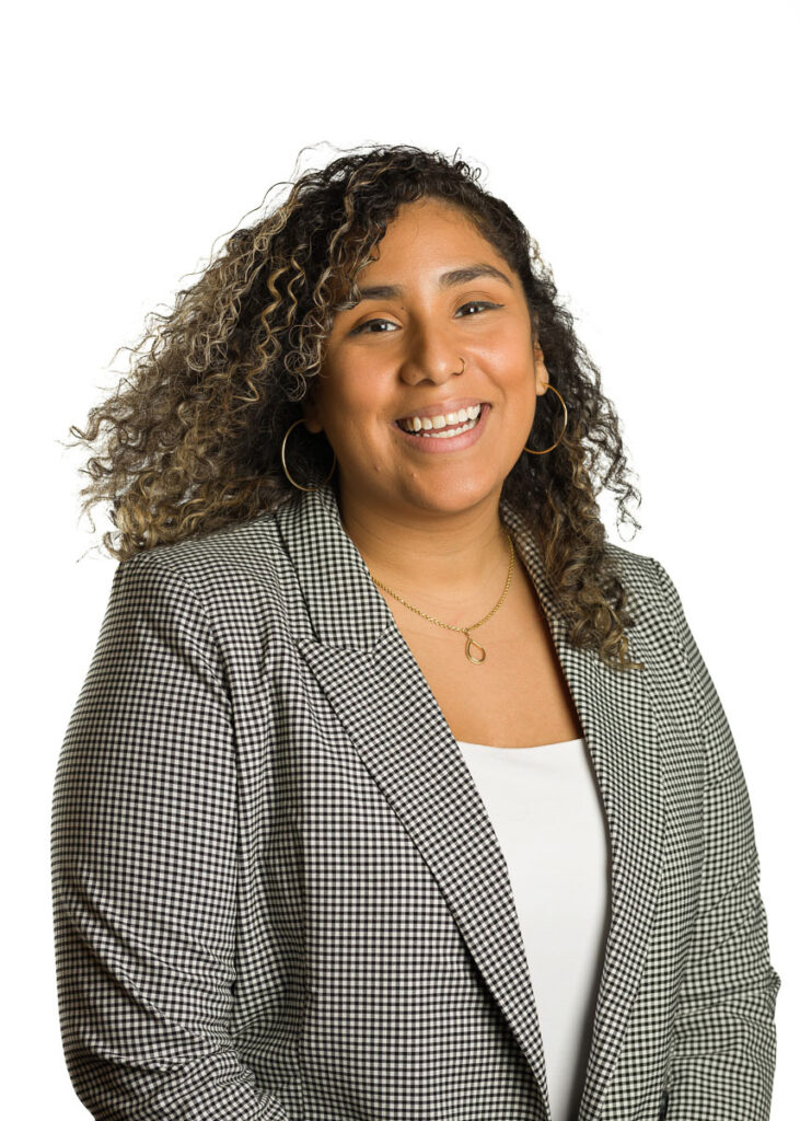 Professional woman smiling confidently in a houndstooth blazer against a white background.