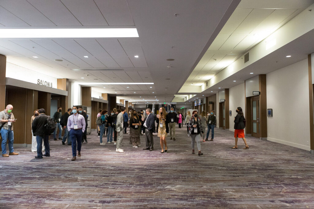 Conference attendees networking in a convention center hallway.