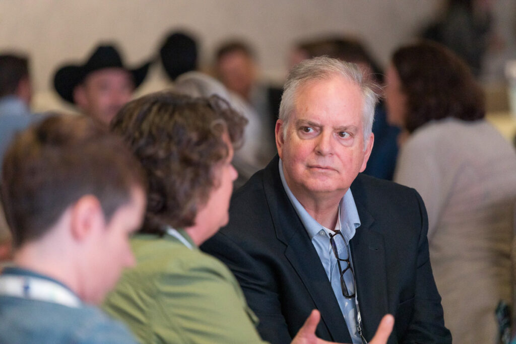 A man in business attire engaging in a serious conversation with colleagues at a professional event or conference.