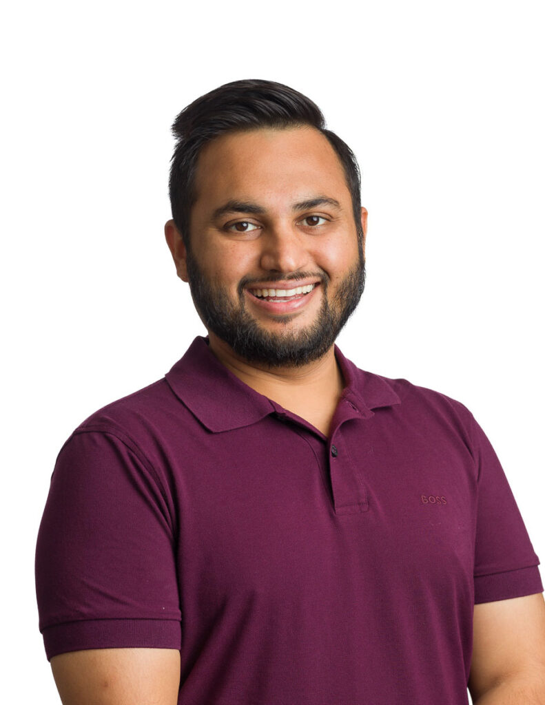 A smiling man wearing a maroon polo shirt against a white background for his corporate headshot.