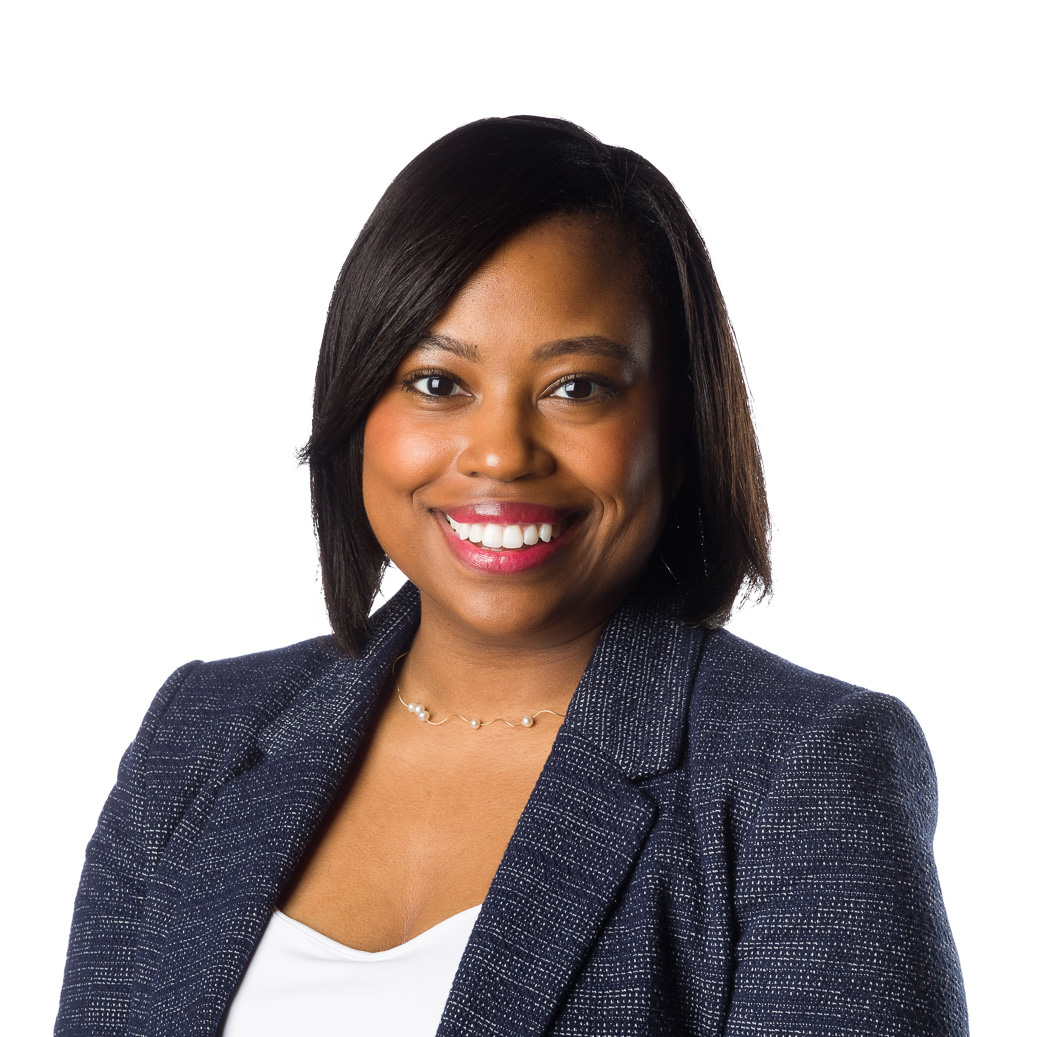 Professional woman with a confident smile wearing a business suit against a white background for her corporate headshot.