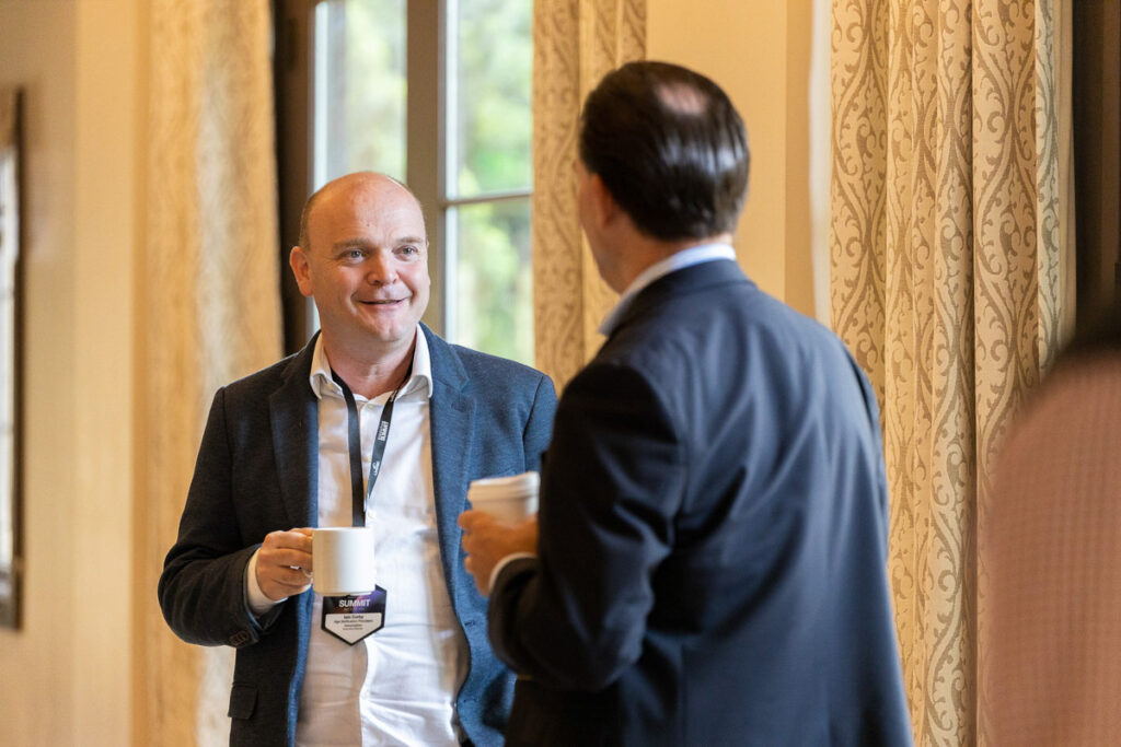 Two professionals engaging in a friendly conversation during a coffee break at a conference.